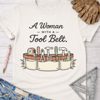 Women's funny woodworking graphic tee shirt for female woodworkers, makers, and DIY builders — Sawdust & Ponytails. White cotton tee with "A Woman With A Tool Belt" text and cartoon tool belt graphic.