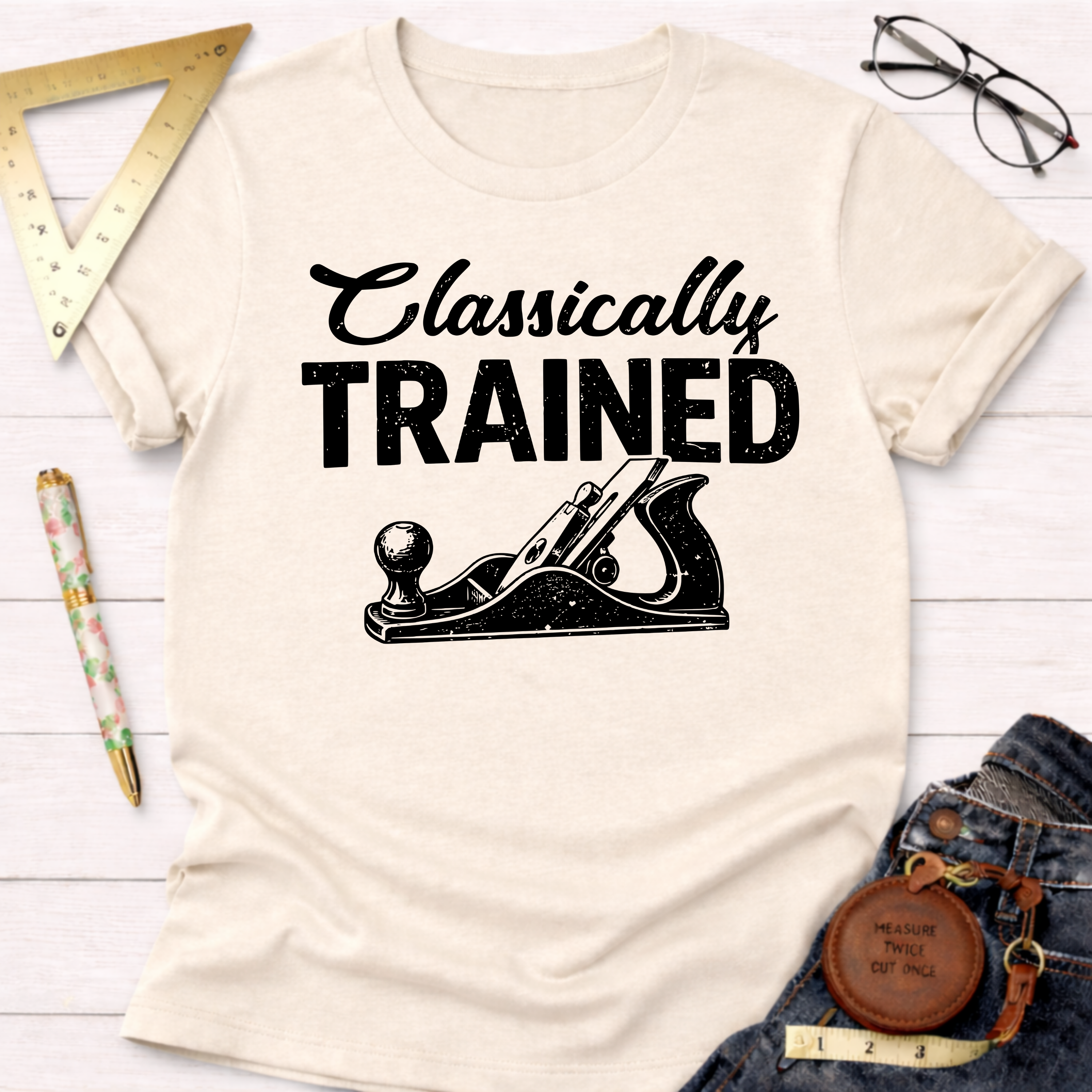 Women's funny woodworking graphic tee shirt for female woodworkers, makers, and DIY builders — Sawdust & Ponytails. Cream t-shirt with "Classically TRAINED" text and hand plane graphic.