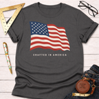 Charcoal gray t-shirt with a waving American flag graphic and "CRAFTED IN AMERICA" text.