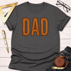 Charcoal gray t-shirt with "DAD" in wood grain letters, styled with glasses, ruler, pen, and jeans.