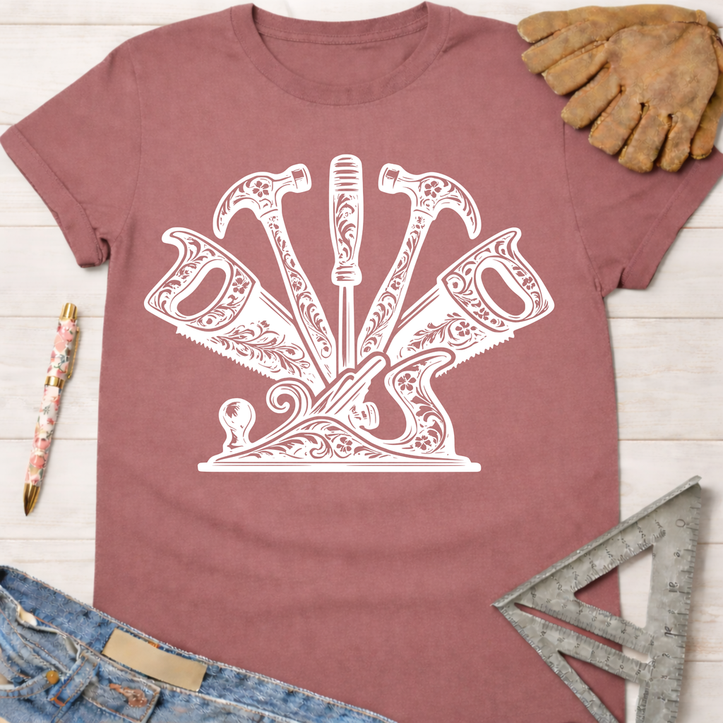 Women's funny woodworking graphic tee shirt for female woodworkers, makers, and DIY builders — Sawdust & Ponytails. Mauve cotton tee with white floral-patterned hammers, saws, and screwdriver design.