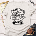 Off-white cotton t-shirt with "Horns, Skills, & A Bad Attitude" graphic featuring a cute, horned character with tools.