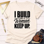 Cream cotton t-shirt with "I Build Like A Woman. Keep Up." in black text, styled with jeans and tools.