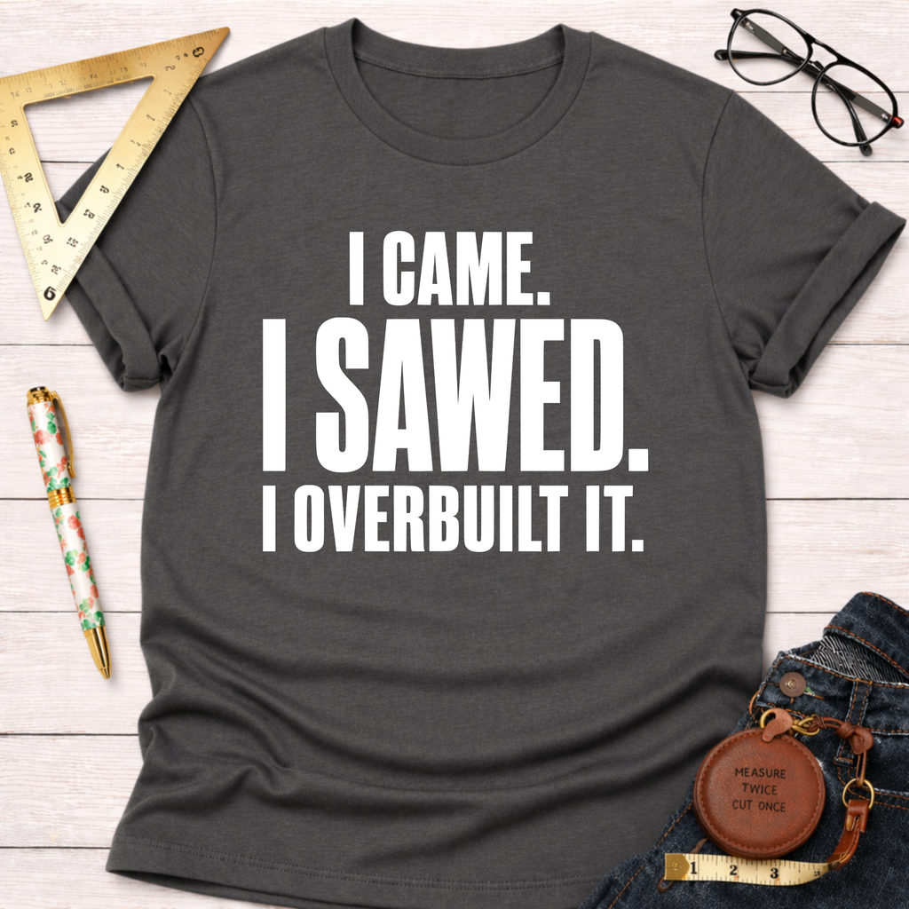 Charcoal gray t-shirt with "I CAME. I SAWED. I OVERBUILT IT." in white text, styled with jeans and tools.
