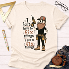 Cream cotton t-shirt with a bearded carpenter holding a drill and the text "I don't have to fix things. I get to fix things.