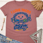 Women's funny woodworking graphic tee shirt for female woodworkers, makers, and DIY builders — Sawdust & Ponytails. Mauve short-sleeve tee with "I Love Tacos and DIY" graphic featuring a happy taco holding tools.