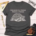 Women's funny woodworking graphic tee shirt for female woodworkers, makers, and DIY builders — Sawdust & Ponytails. Dark gray crew neck t-shirt with "I Reckon I'll Finish When I Finish" and a white turtle graphic.