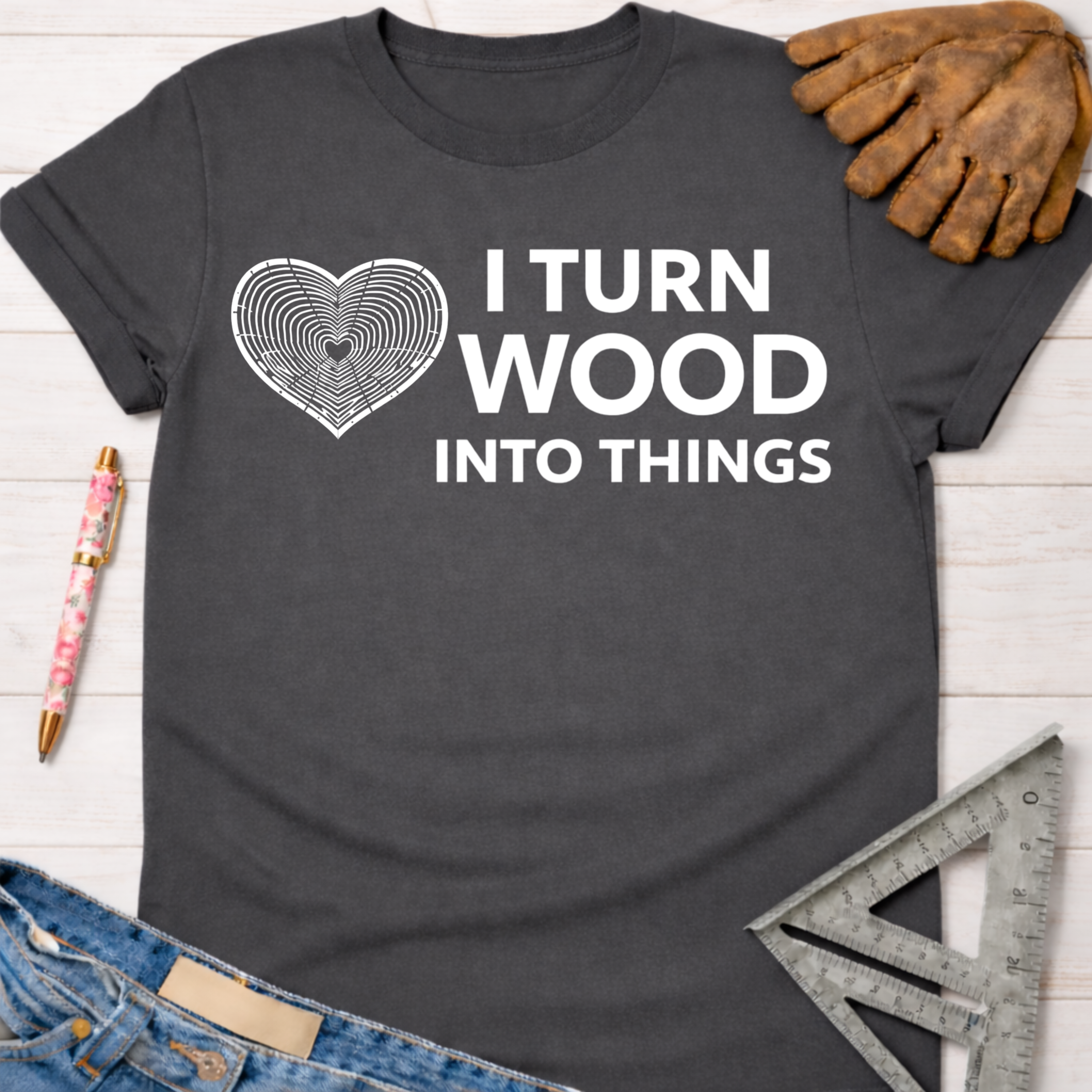 Women's funny woodworking graphic tee shirt for female woodworkers, makers, and DIY builders — Sawdust & Ponytails. Dark gray t-shirt with "I Turn Wood Into Things" text and a heart-shaped wood grain graphic.