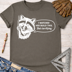 Women's funny woodworking graphic tee shirt for female woodworkers, makers, and DIY builders — Sawdust & Ponytails. Dark gray t-shirt with a white graphic of a raccoon saying "I watched her build this. She's terrifying.