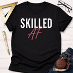 Black cotton t-shirt with "Skilled AF" in white and pink, styled with jeans, ruler, and glasses.