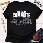 Black cotton t-shirt with "THE DAILY COMMUTE" text and a stick figure walking from a house to a workshop.