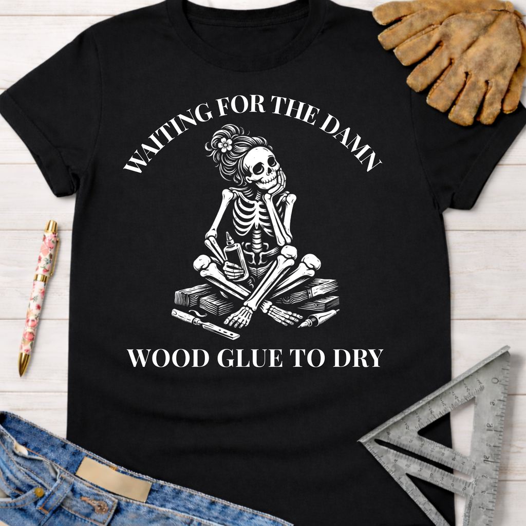 Women's funny woodworking graphic tee shirt for female woodworkers, makers, and DIY builders — Sawdust & Ponytails. Black cotton t-shirt with a white skeleton graphic, "Waiting For The Damn Wood Glue To Dry" text.