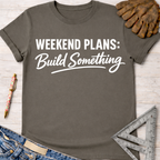 Charcoal grey "Weekend Plans: Build Something" graphic tee with work glove, pen, jeans, and ruler.