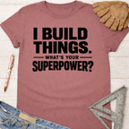 Women's funny woodworking graphic tee shirt for female woodworkers, makers, and DIY builders — Sawdust & Ponytails. Mauve t-shirt with "I BUILD THINGS. WHAT'S YOUR SUPERPOWER?" in black text.