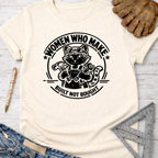 Women's funny woodworking graphic tee shirt for female woodworkers, makers, and DIY builders — Sawdust & Ponytails. Cream t-shirt with a black graphic of a cat wearing goggles and overalls, holding a hammer and wrench, encircled by "WOMEN WHO MAKE. BUILT NOT BOUGHT.
