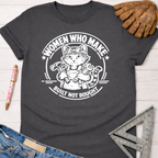 Women's funny woodworking graphic tee shirt for female woodworkers, makers, and DIY builders — Sawdust & Ponytails. Dark gray cotton t-shirt with a white graphic of a cat in goggles and overalls holding a hammer and wrench, encircled by "Women Who Make. Built Not Bought.