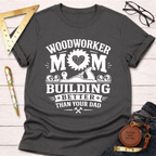Women's funny woodworking graphic tee shirt for female woodworkers, makers, and DIY builders — Sawdust & Ponytails. Dark gray crewneck t-shirt with "Woodworker Mom Building Better Than Your Dad" graphic.