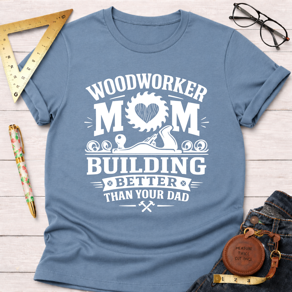 Women's funny woodworking graphic tee shirt for female woodworkers, makers, and DIY builders — Sawdust & Ponytails. Light blue cotton tee with "Woodworker Mom Building Better Than Your Dad" graphic.