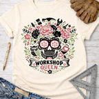Women's funny woodworking graphic tee shirt for female woodworkers, makers, and DIY builders — Sawdust & Ponytails. Cream t-shirt with a floral skull and tools graphic, "Workshop Queen" banner.