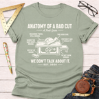 Women's funny woodworking graphic tee shirt for female woodworkers, makers, and DIY builders — Sawdust & Ponytails. Light green cotton tee with "Anatomy of a Bad Cut" table saw graphic.
