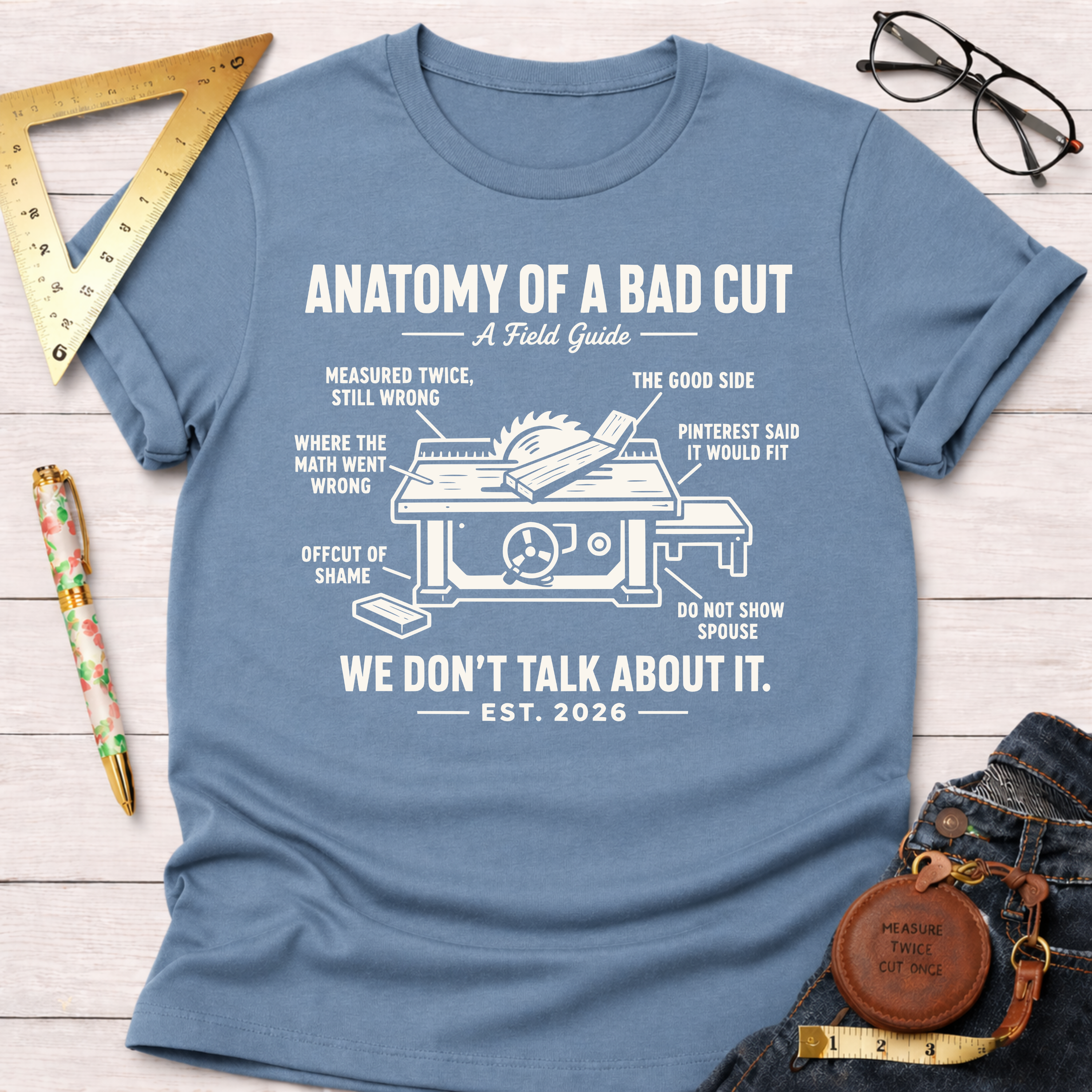 Women's funny woodworking graphic tee shirt for female woodworkers, makers, and DIY builders — Sawdust & Ponytails. Light blue cotton tee with "Anatomy of a Bad Cut" table saw graphic.