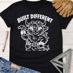 Black cotton "Built Different" tee with a cute Highland cow builder graphic, work gloves, and jeans. Women's funny woodworking graphic tee shirt for female woodworkers, makers, and DIY builders — Sawdust & Ponytails.