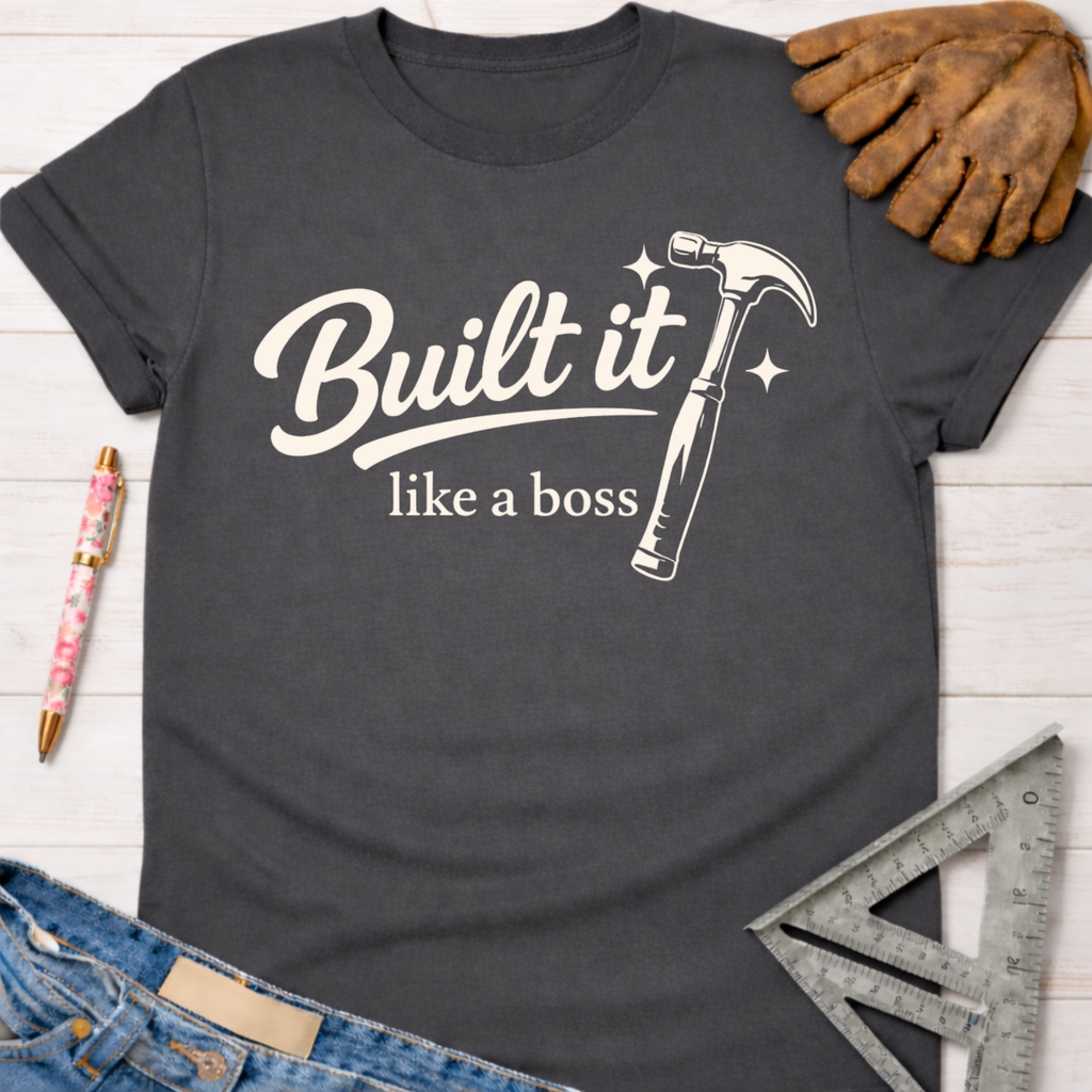 Women's funny woodworking graphic tee shirt for female woodworkers, makers, and DIY builders — Sawdust & Ponytails. Dark gray cotton tee with "Built it like a boss" text and hammer graphic.