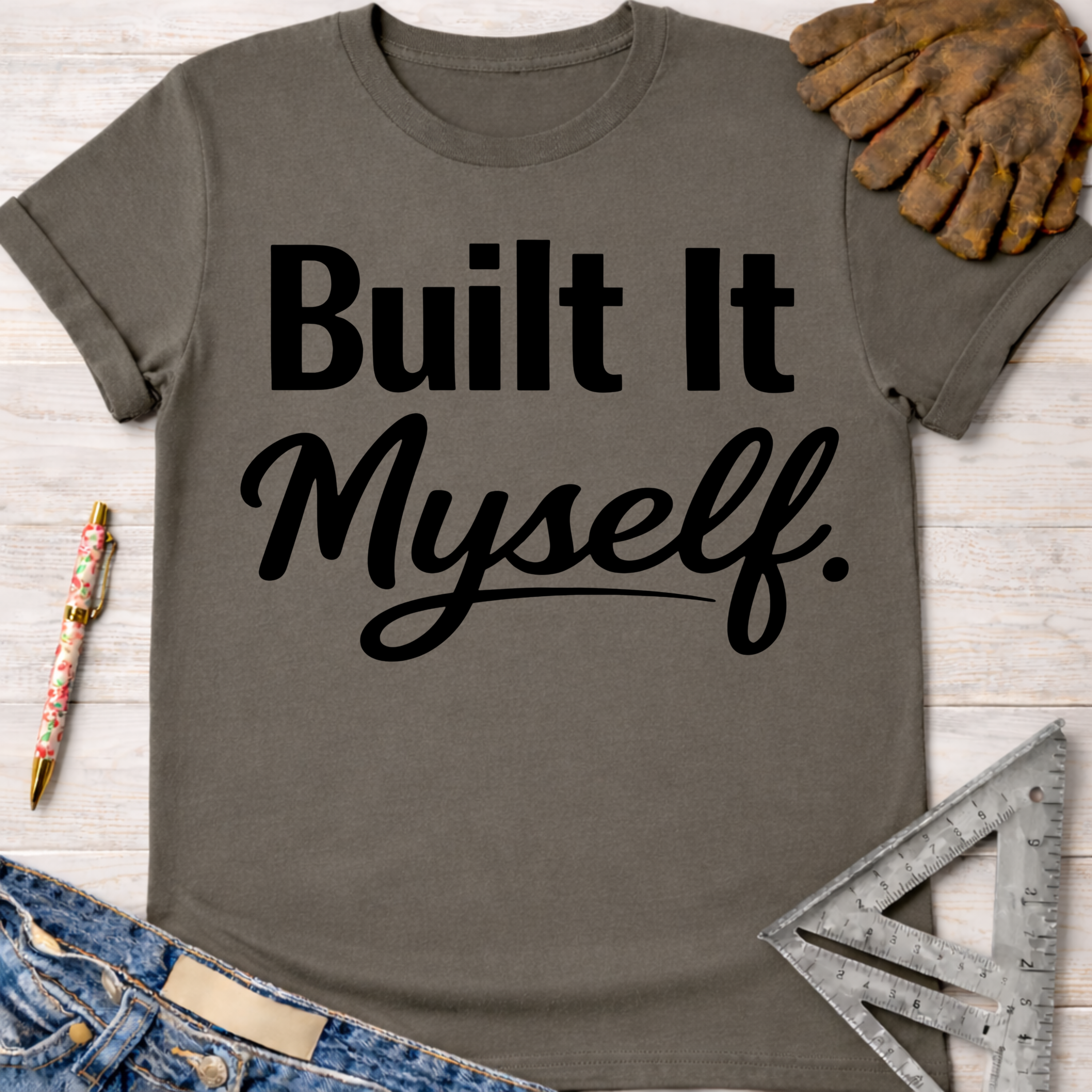 Women's funny woodworking graphic tee shirt for female woodworkers, makers, and DIY builders — Sawdust & Ponytails. Dark gray cotton tee with "Built It Myself" in black script.