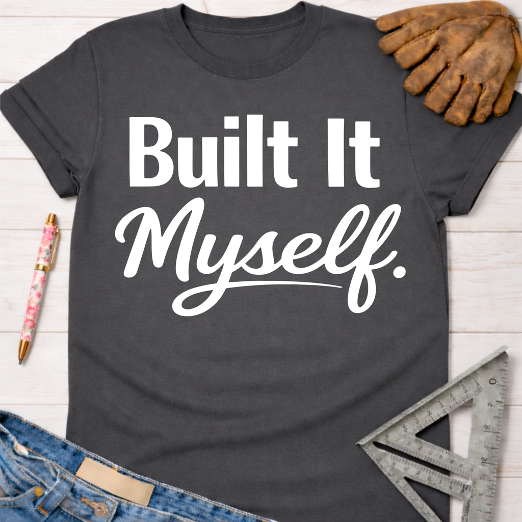 Women's funny woodworking graphic tee shirt for female woodworkers, makers, and DIY builders — Sawdust & Ponytails. Dark gray t-shirt with "Built It Myself." in white text, styled with jeans, a pen, work glove, and a speed square.