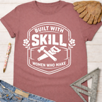 Women's funny woodworking graphic tee shirt for female woodworkers, makers, and DIY builders — Sawdust & Ponytails. Mauve cotton tee with "Built With Skill Women Who Make" graphic.