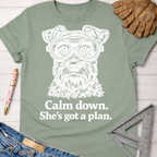Women's funny woodworking graphic tee shirt for female woodworkers, makers, and DIY builders — Sawdust & Ponytails. Sage green cotton t-shirt with a white graphic of a dog wearing safety goggles and the text "Calm down. She's got a plan.