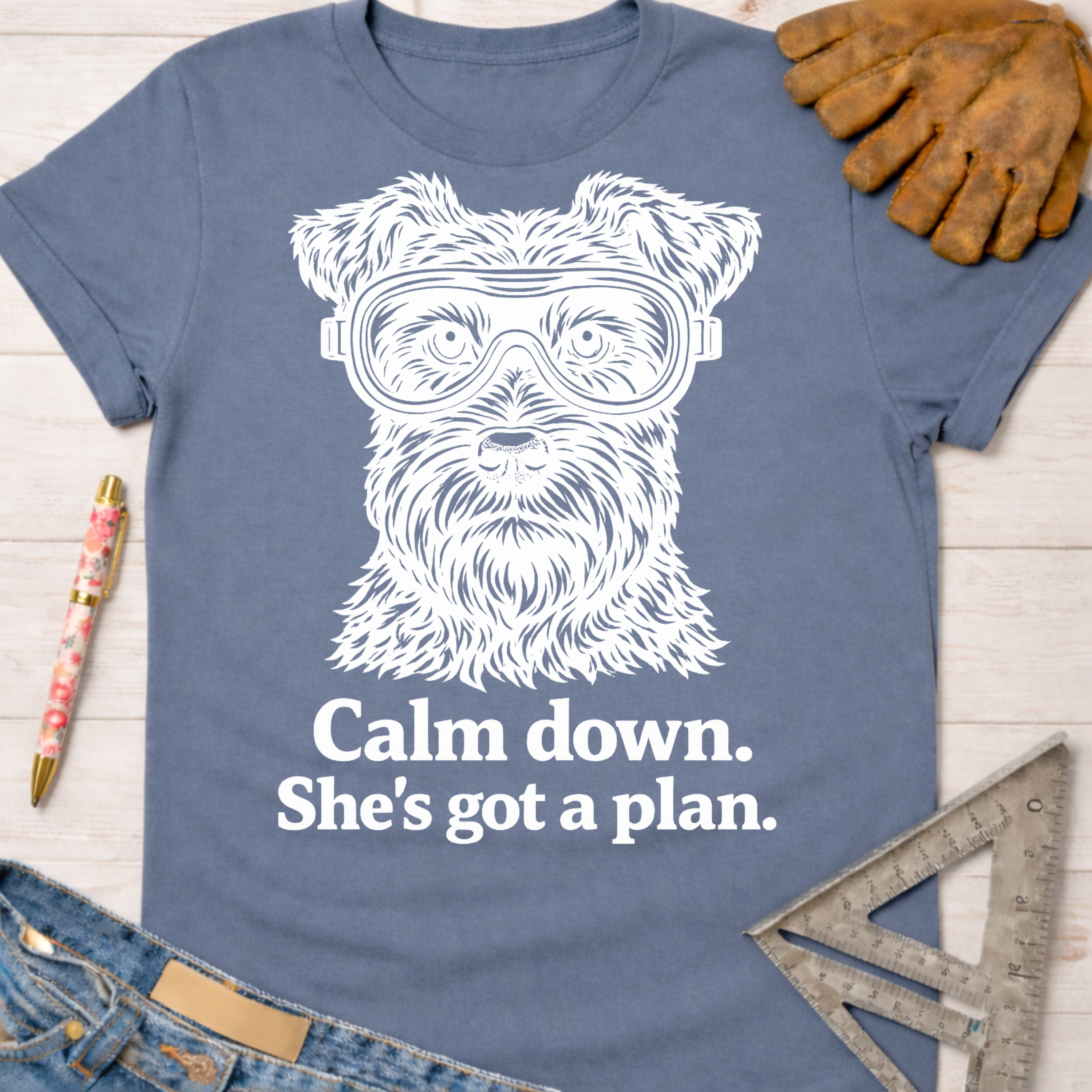 Women's funny woodworking graphic tee shirt for female woodworkers, makers, and DIY builders — Sawdust & Ponytails. Blue cotton tee with a white Schnauzer wearing goggles and "Calm down. She's got a plan." text.