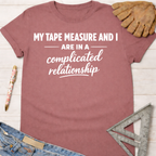 Women's funny woodworking graphic tee shirt for female woodworkers, makers, and DIY builders — Sawdust & Ponytails. Mauve cotton tee with "My Tape Measure And I Are In A Complicated Relationship" text.