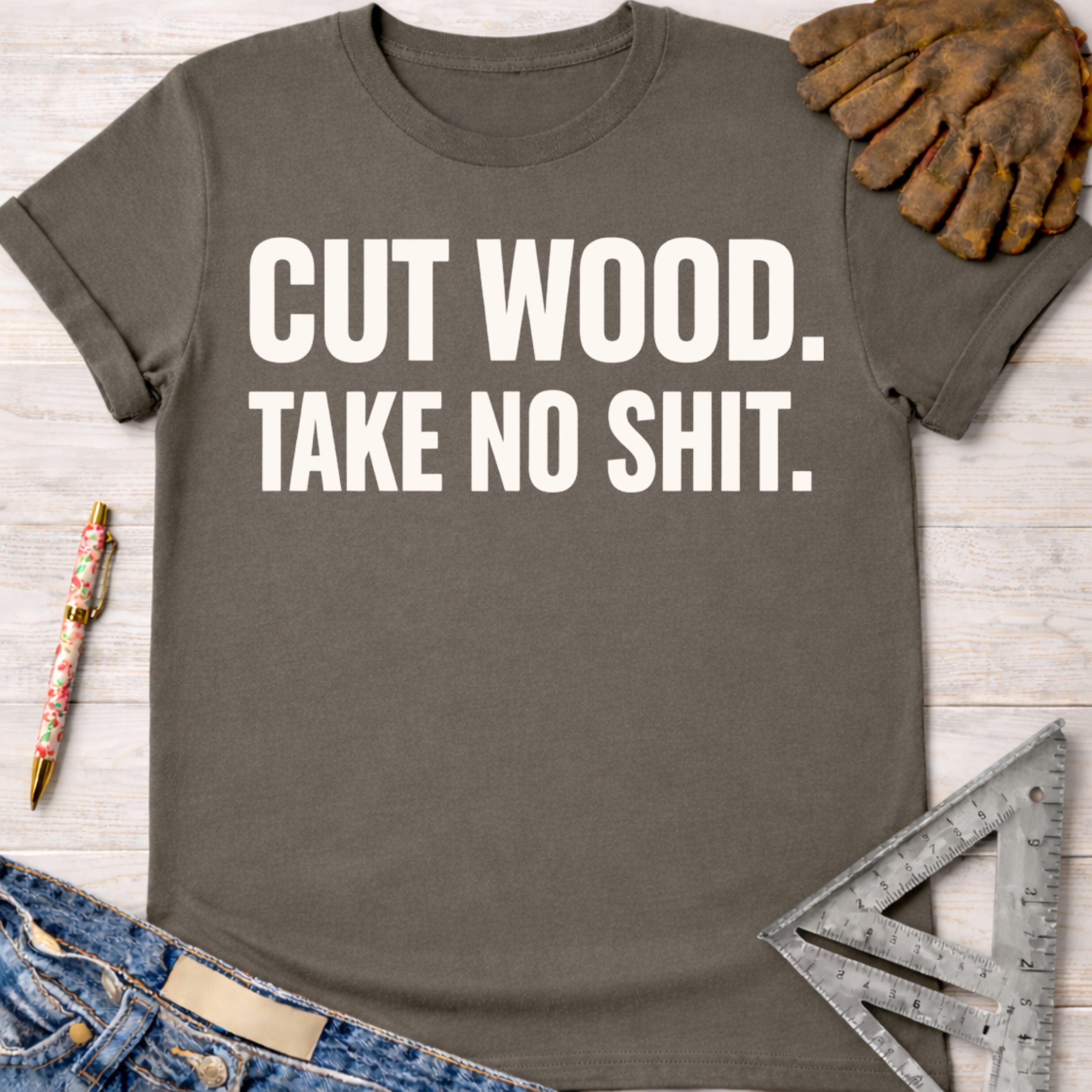 Women's funny woodworking graphic tee shirt for female woodworkers, makers, and DIY builders — Sawdust & Ponytails. Dark gray cotton t-shirt with "CUT WOOD. TAKE NO SHIT." in white text.