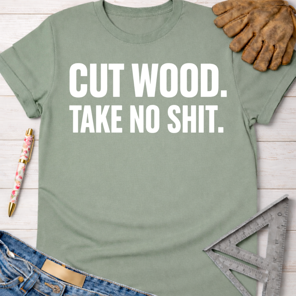 Women's funny woodworking graphic tee shirt for female woodworkers, makers, and DIY builders — Sawdust & Ponytails. Sage green cotton tee with "CUT WOOD. TAKE NO SHIT." in white text.
