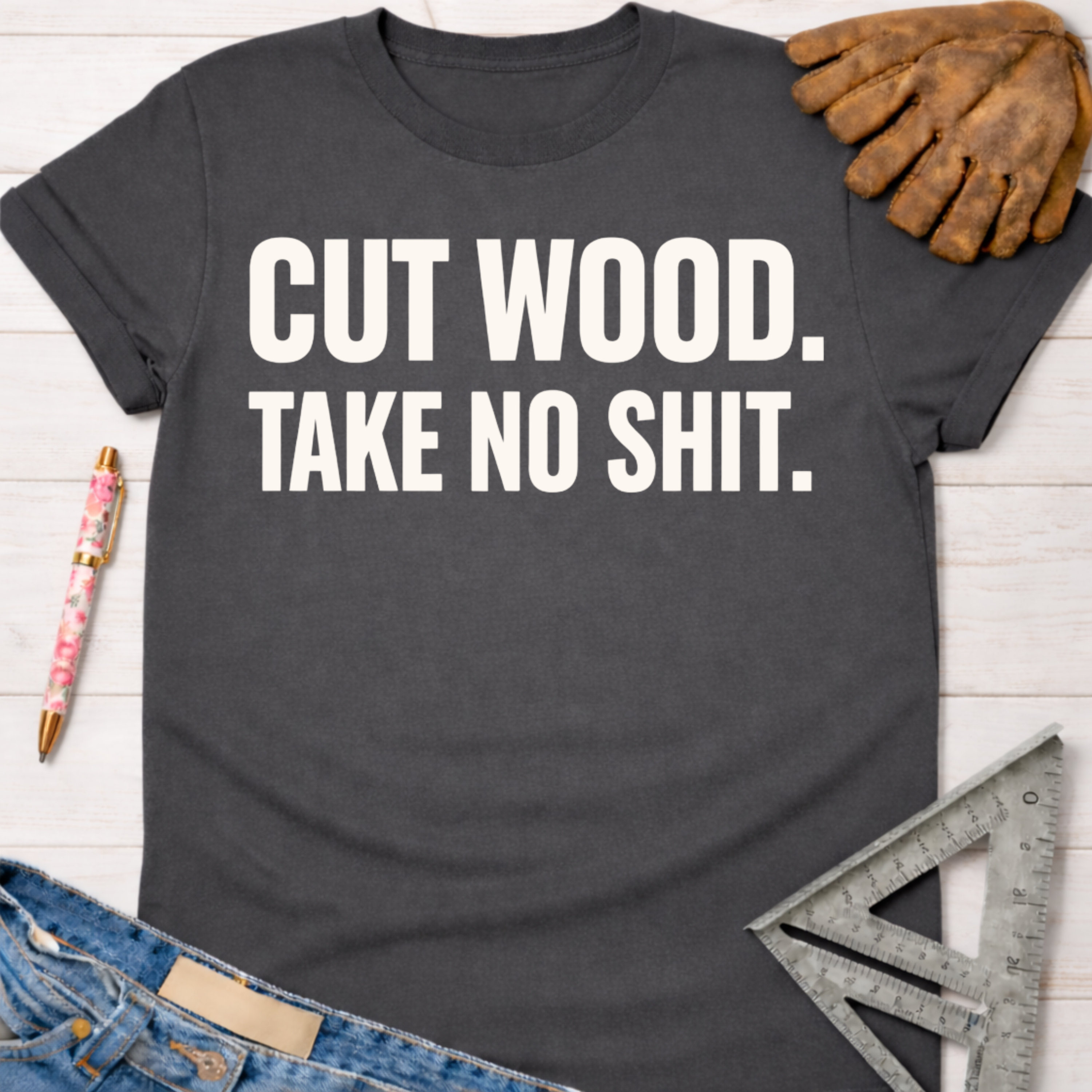 Charcoal gray women's "Cut Wood. Take No Shit." graphic tee with work gloves, jeans, and ruler. Women's funny woodworking graphic tee shirt for female woodworkers, makers, and DIY builders — Sawdust & Ponytails