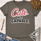 Women's funny woodworking graphic tee shirt for female woodworkers, makers, and DIY builders — Sawdust & Ponytails. Dark gray cotton tee with "Cute BUT CAPABLE" in pink and black.