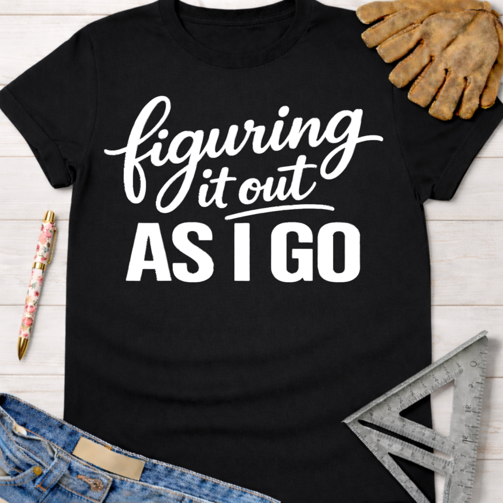 Black cotton "Figuring It Out As I Go" graphic tee for women, with work glove, pen, and ruler.