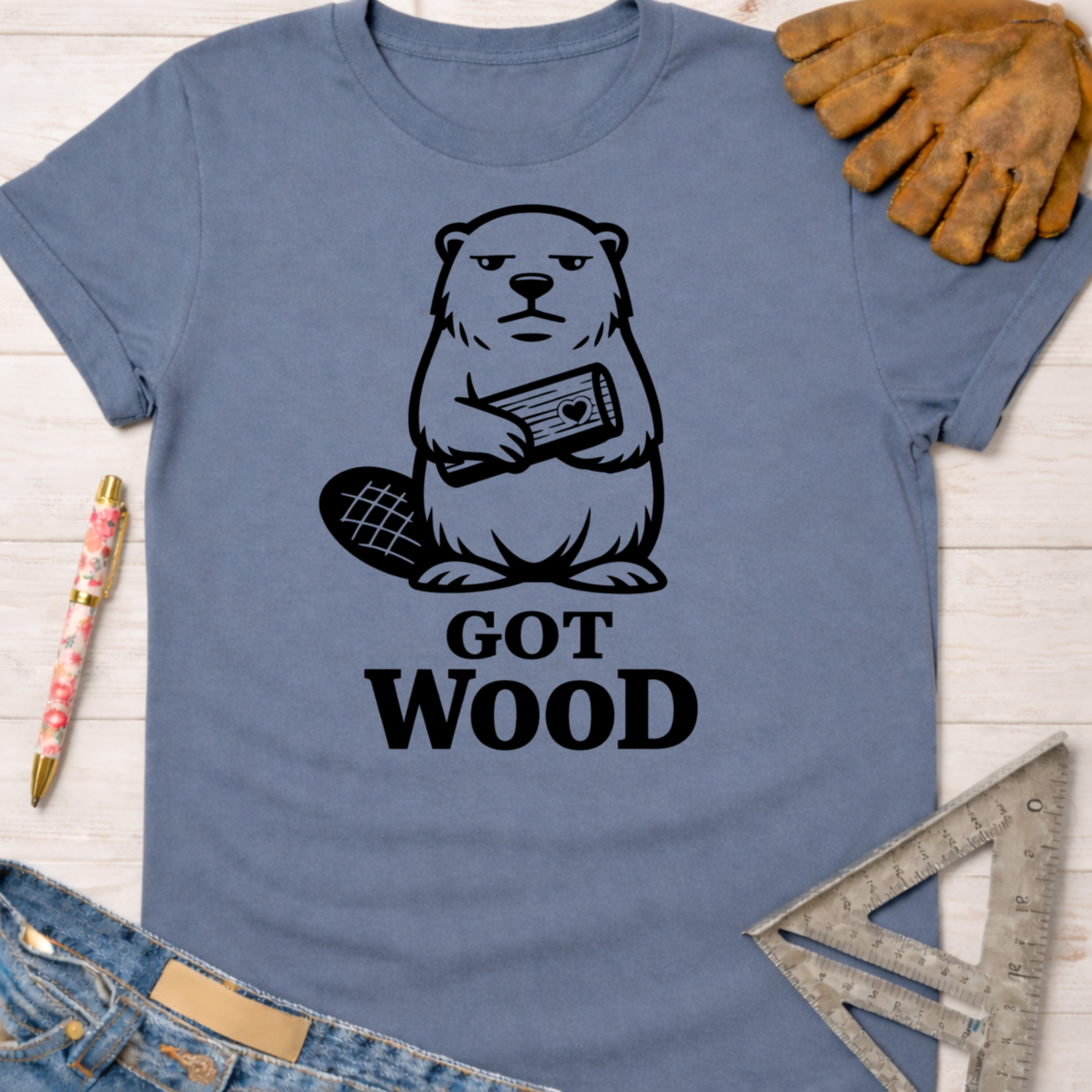 Women's funny woodworking graphic tee shirt for female woodworkers, makers, and DIY builders — Sawdust & Ponytails. Blue cotton tee with a grumpy beaver holding wood and "Got Wood?" text.