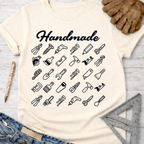 Women's funny woodworking graphic tee shirt for female woodworkers, makers, and DIY builders — Sawdust & Ponytails. Cream t-shirt with "Handmade" and black tool icons.