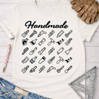 Women's funny woodworking graphic tee shirt for female woodworkers, makers, and DIY builders — Sawdust & Ponytails. Cream t-shirt with "Handmade" and black tool icons.