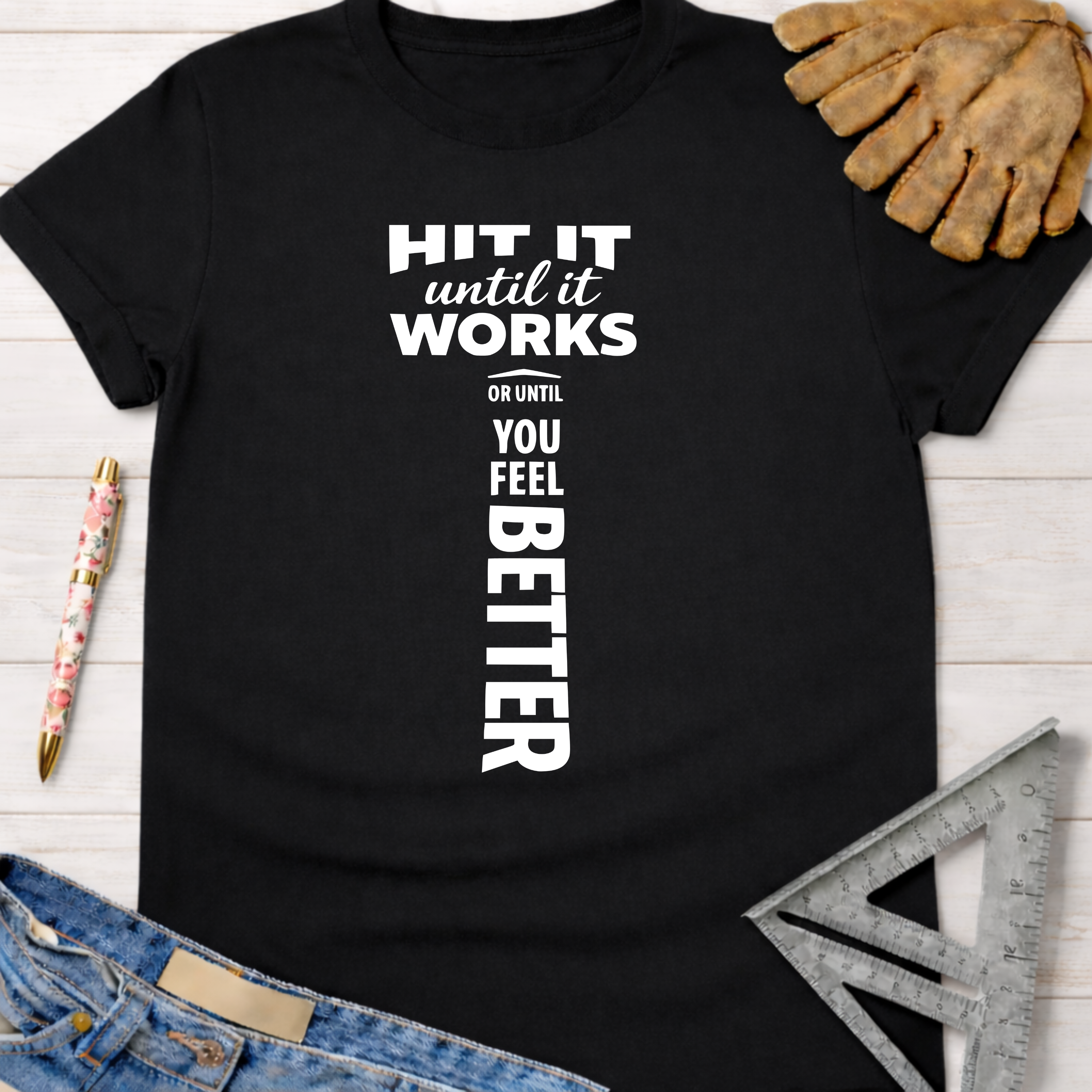 Black cotton t-shirt with "HIT IT until it works OR UNTIL YOU FEEL BETTER" text, work glove, and ruler. Women's funny woodworking graphic tee shirt for female woodworkers, makers, and DIY builders — Sawdust & Ponytails.
