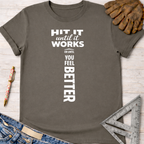 Women's funny woodworking graphic tee shirt for female woodworkers, makers, and DIY builders — Sawdust & Ponytails. Charcoal gray cotton t-shirt with "HIT IT until it works OR UNTIL YOU FEEL BETTER" in white text, styled like a hammer.