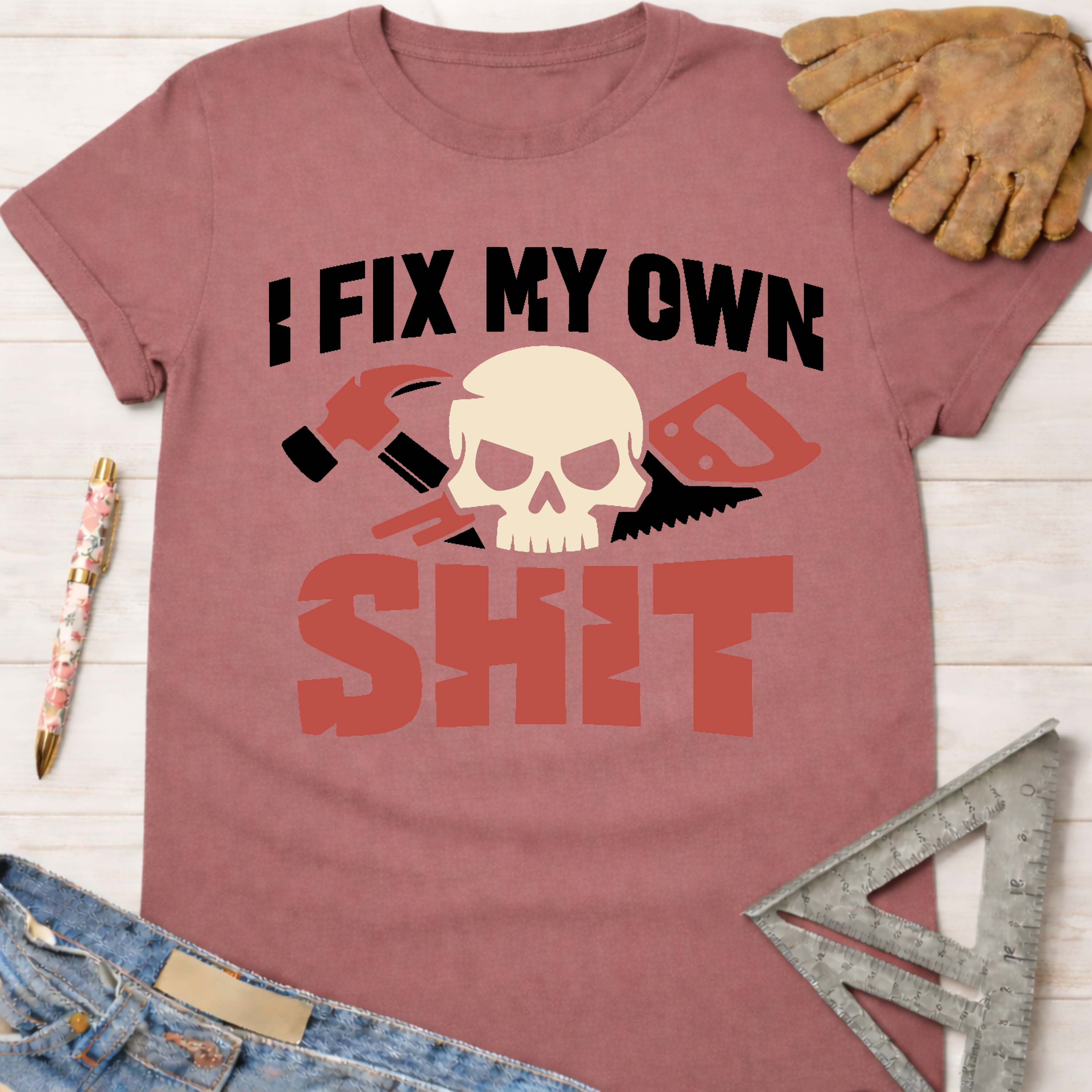 Women's funny woodworking graphic tee shirt for female woodworkers, makers, and DIY builders — Sawdust & Ponytails. Mauve cotton t-shirt with "I FIX MY OWN SHIT" text, skull, hammer, and saw graphic.