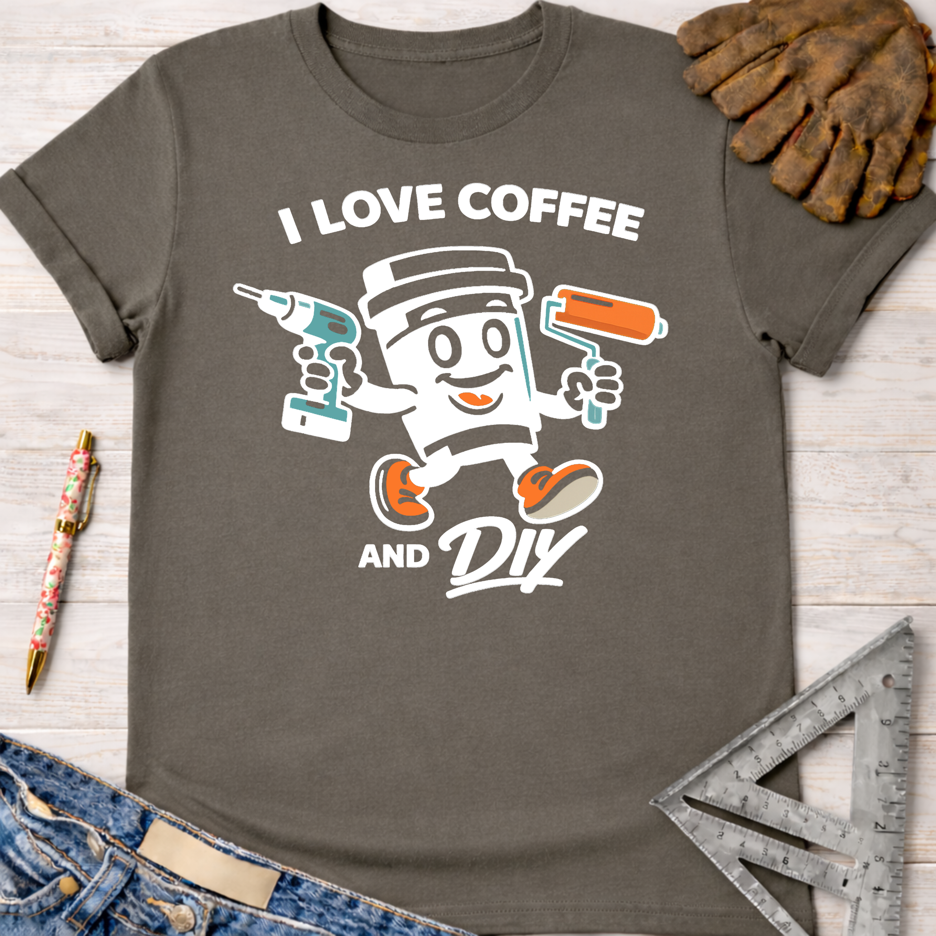 Women's funny woodworking graphic tee shirt for female woodworkers, makers, and DIY builders — Sawdust & Ponytails. Charcoal gray cotton tee with "I Love Coffee and DIY" text and a coffee cup character holding a drill and paint roller.