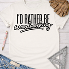 Women's funny woodworking graphic tee shirt for female woodworkers, makers, and DIY builders — Sawdust & Ponytails. White cotton tee with "I'd Rather Be Woodworking" in black text.