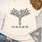 Women's funny woodworking graphic tee shirt for female woodworkers, makers, and DIY builders — Sawdust & Ponytails. Cream t-shirt with a black floral hammer "MAKER" graphic.