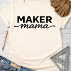 Women's funny woodworking graphic tee shirt for female woodworkers, makers, and DIY builders — Sawdust & Ponytails. Cream "Maker Mama" t-shirt with black text, jeans, work glove, pen, and ruler.