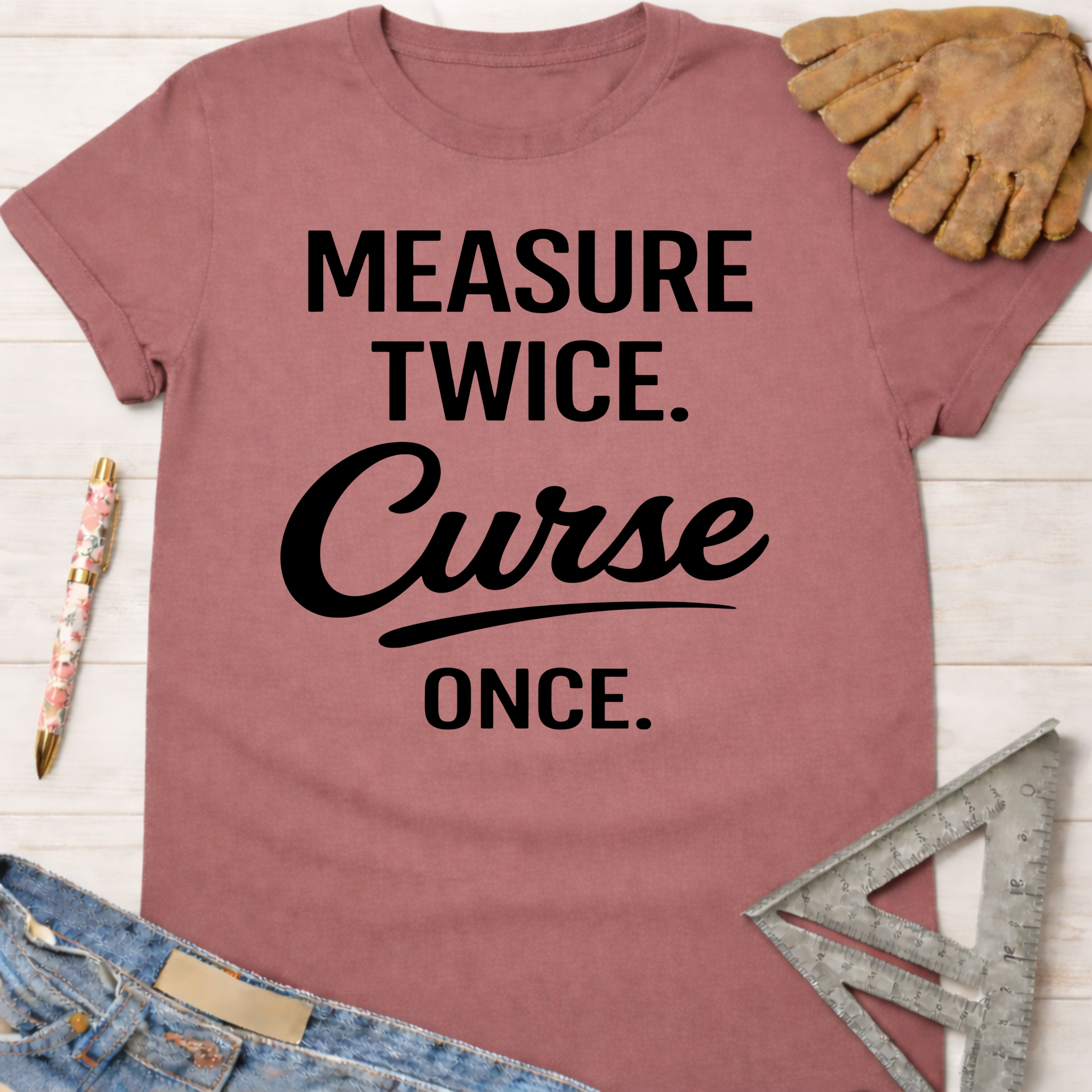 Women's funny woodworking graphic tee shirt for female woodworkers, makers, and DIY builders — Sawdust & Ponytails. Mauve cotton t-shirt with "Measure Twice. Curse Once." in black text.