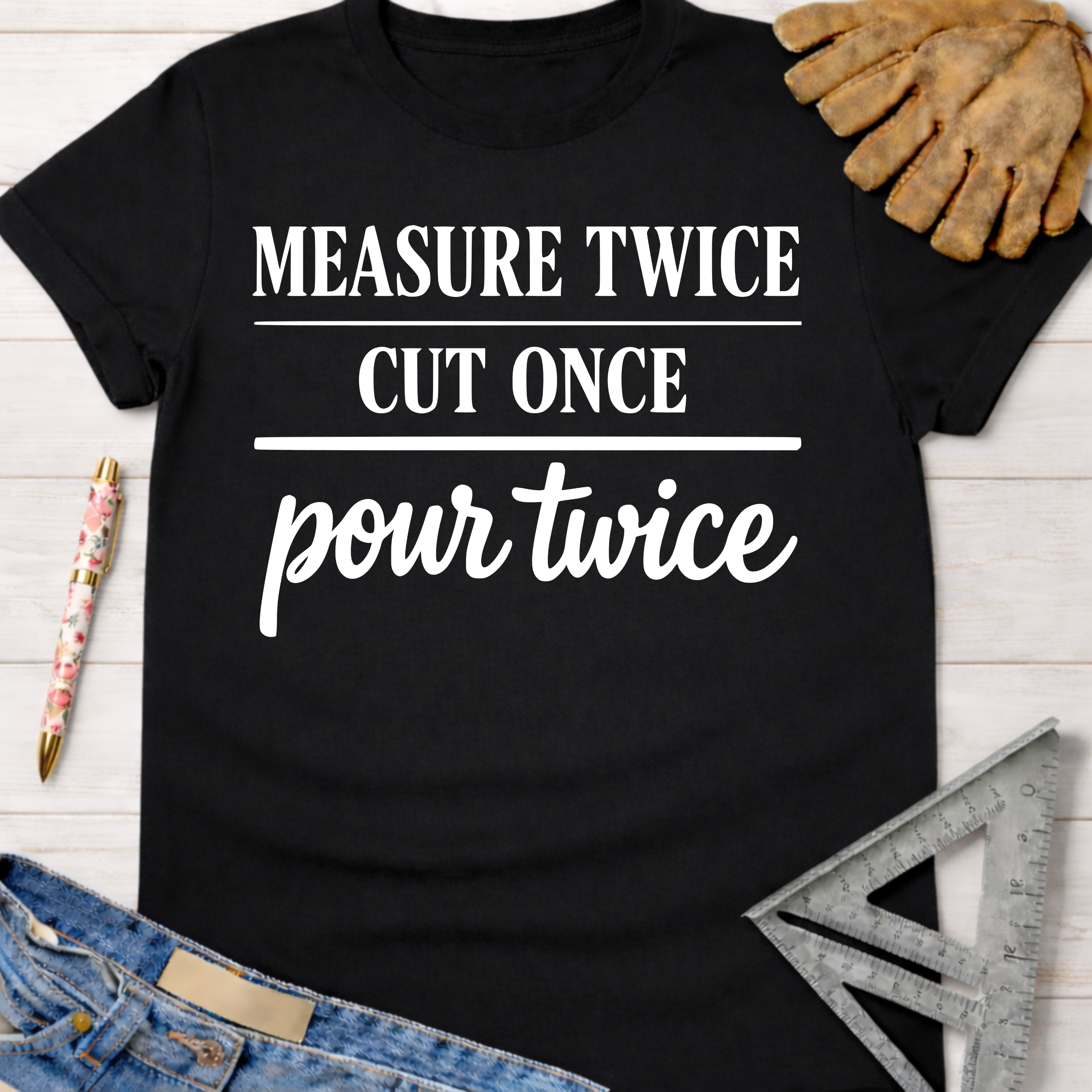 Women's funny woodworking graphic tee shirt for female woodworkers, makers, and DIY builders — Sawdust & Ponytails. Black cotton tee with "MEASURE TWICE CUT ONCE pour twice" in white text.